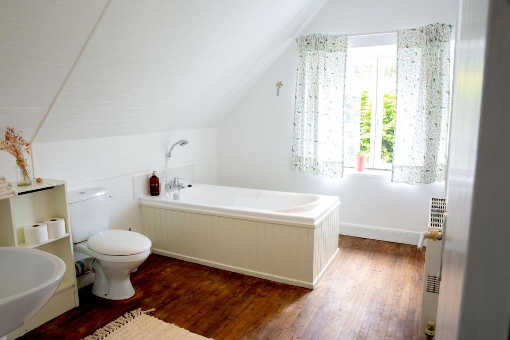 une salle de bain avec baignoire et toilettes et une fenêtre dans l'établissement Chambre privée à la campagne avec deux lits doubles petit déjeuner inclus, à Laniscat