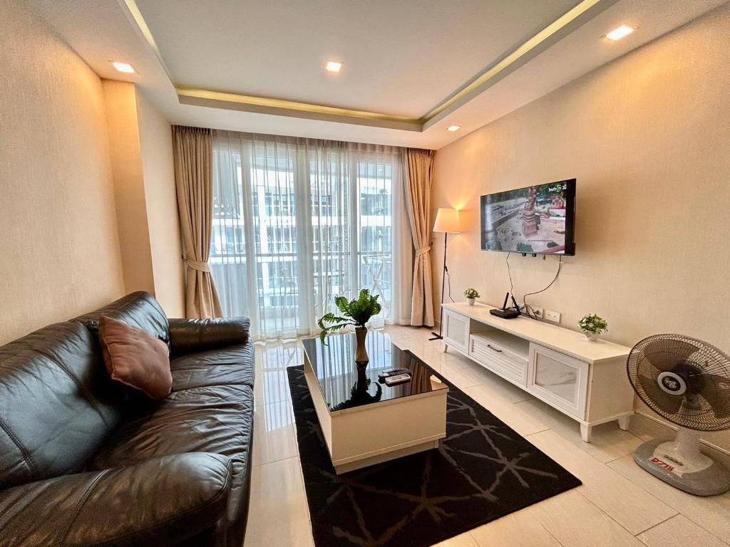 Una sala de estar con un sofá de cuero y un televisor. en Grand Avenue Residence condominium, en Pattaya central