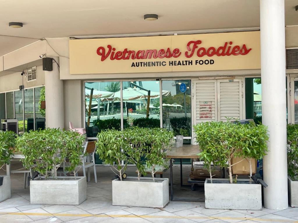 a restaurant with a table and potted trees in front of it at Rustic Elegance By The Lake Studio Cabin In Jlt in Dubai