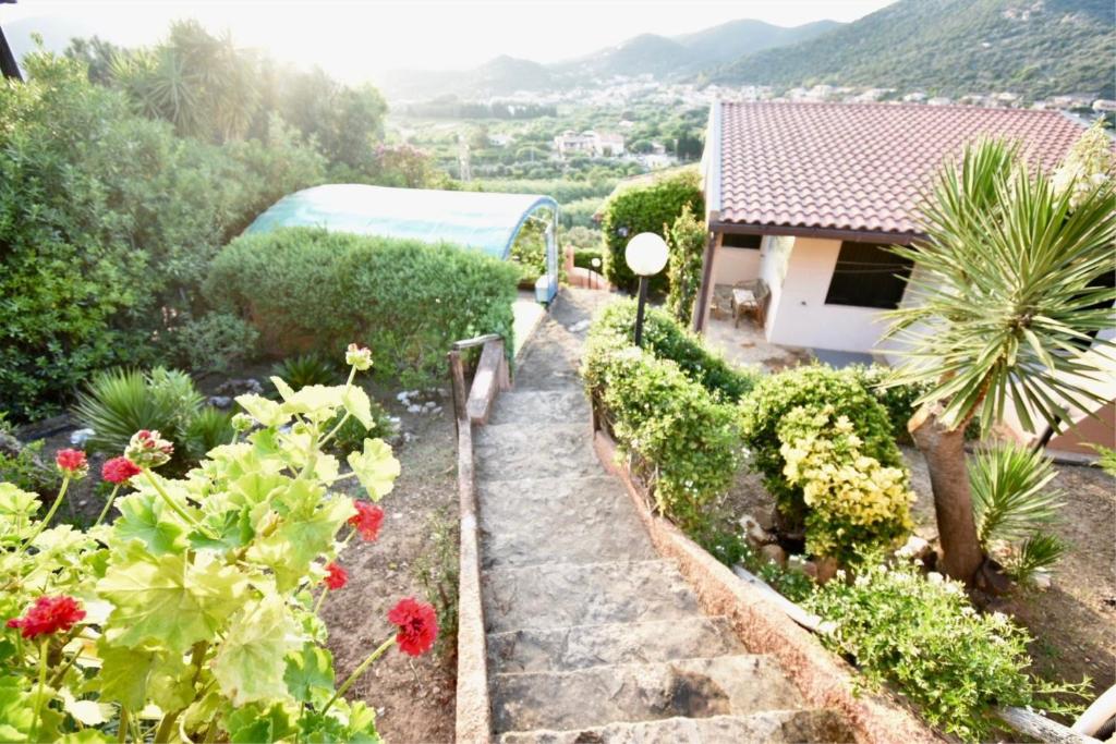 a garden with flowers and a house in the background at Villa giulia in Domus de Maria