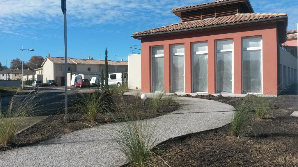 a building with a sidewalk next to a street at Résidence Les Alizés in La Brede