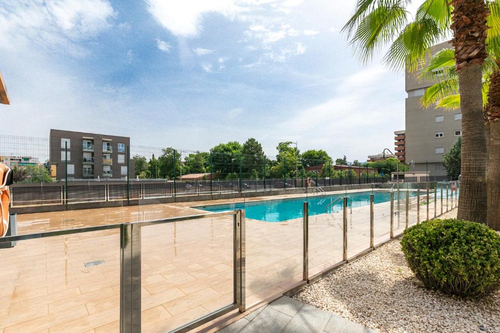 a swimming pool with a fence and a palm tree at Holiday Granada Ático Piscina y Parking in Granada