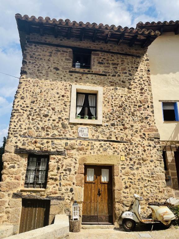 a stone building with a scooter parked in front of it at ViLA VELLA 1 in Santa Pau