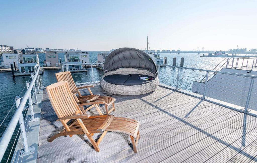 a deck with two chairs and a boat on the water at 10 Ost in Olpenitz