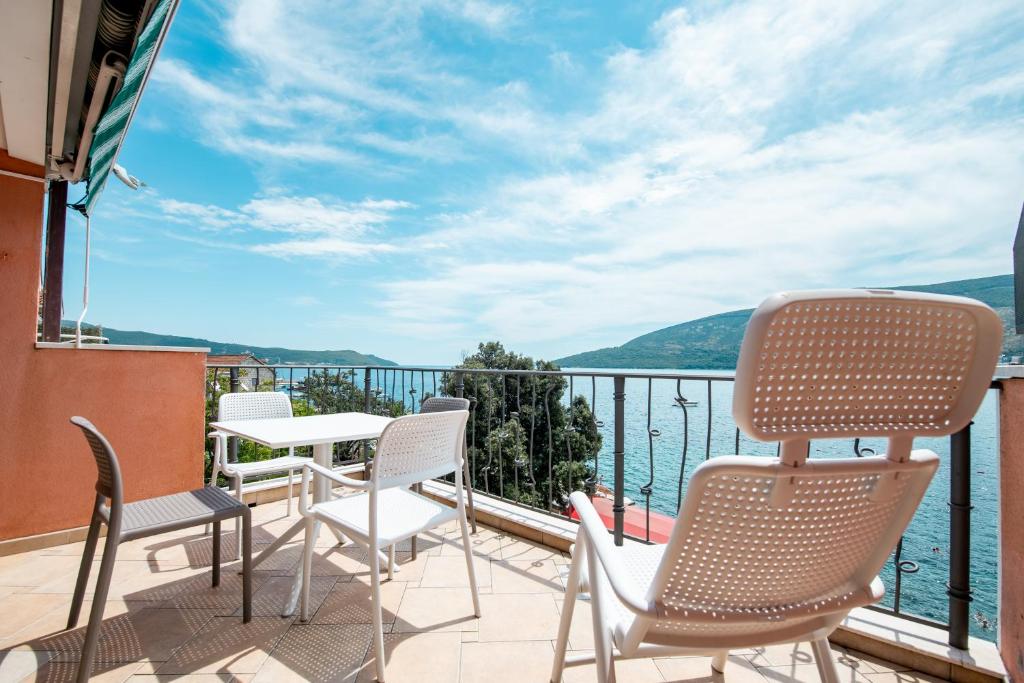 een balkon met stoelen en een tafel en uitzicht op het water bij Boka Apartment 1 in Herceg-Novi
