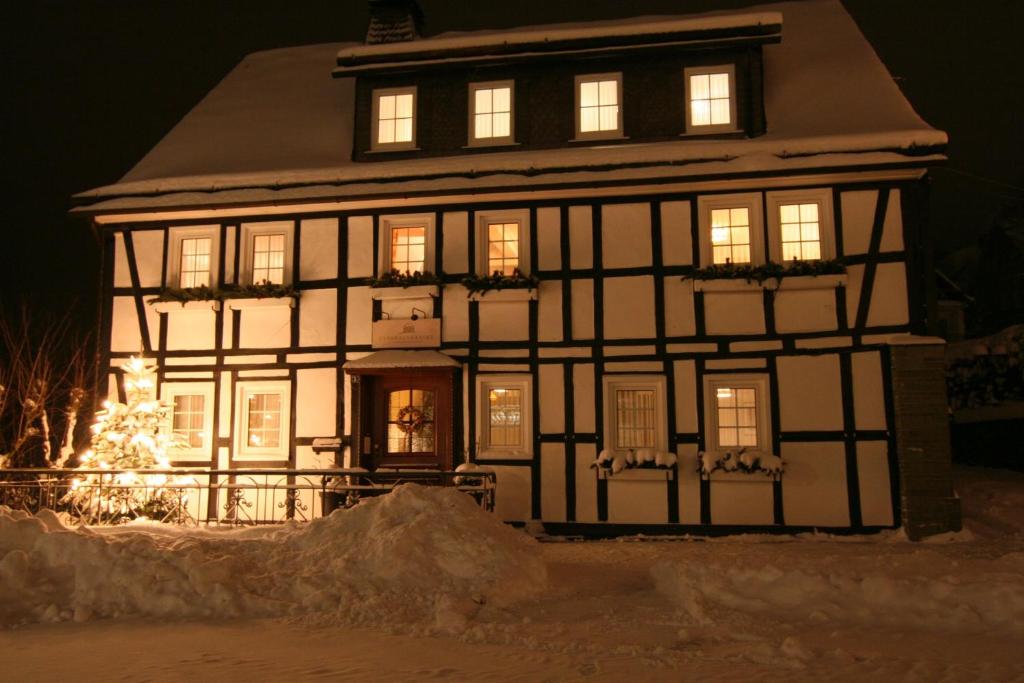 een huis dat verlicht is in de sneeuw bij Landhaus Gnacke in Schmallenberg