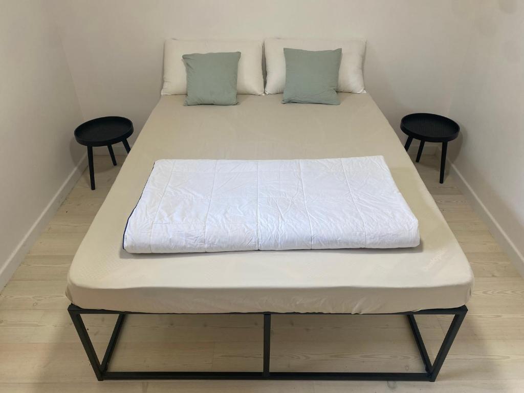 - un lit dans une petite pièce avec deux tabourets dans l'établissement Jolie maison rénovée avec jardin proche Paris, à Montigny-lès-Cormeilles