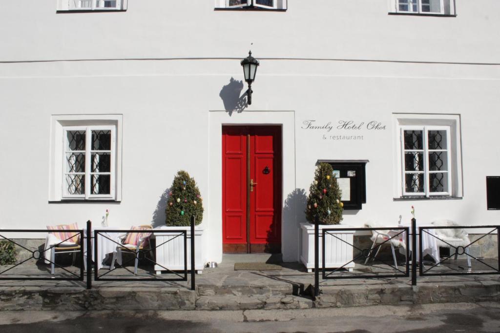 uma porta vermelha num edifício branco com árvores de Natal em Family Hotel Okoř em Okoř