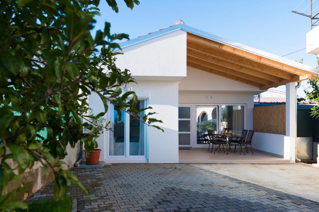 a white house with a wooden roof and a patio at Apartment Bokanjac Free Covered Parking & Quiet Neighborhood in Zadar
