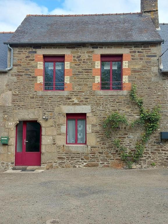 Cette ancienne maison en pierre est dotée de portes et de fenêtres rouges. dans l'établissement Maison Bretonne, à La Boussac