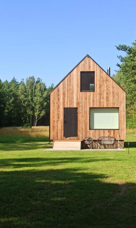 a wooden barn with a large window on a field at Dom w lesie in Przytuły