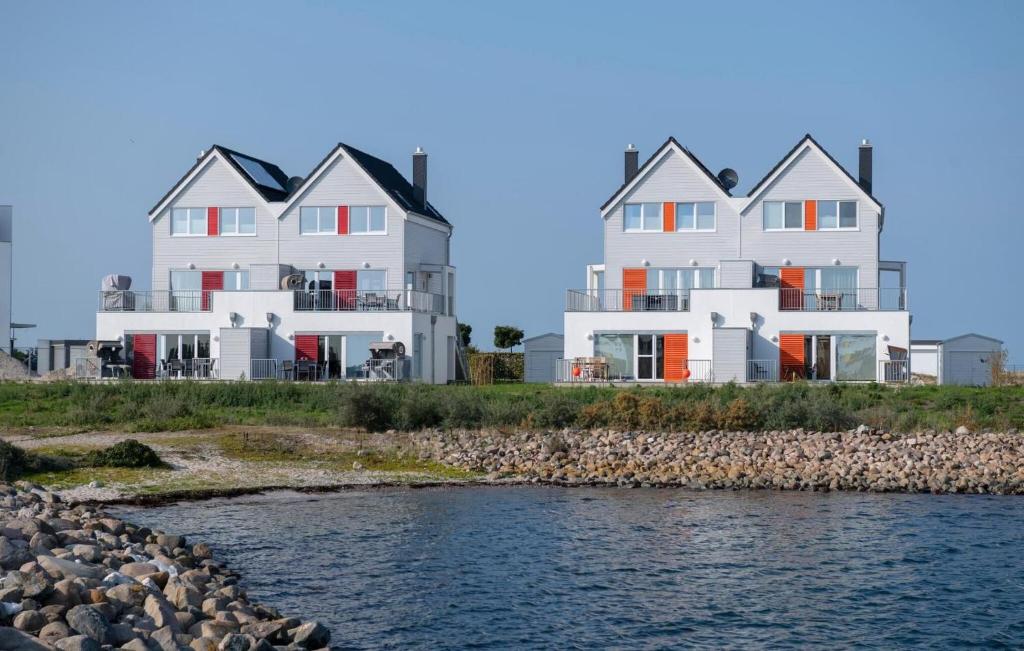 two large white houses next to a body of water at B-Lodge in Olpenitz