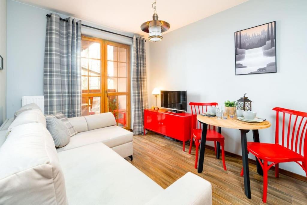 a living room with a white couch and a table at VacationClub - Leśny Dom 18A Apartament 25 in Karpacz