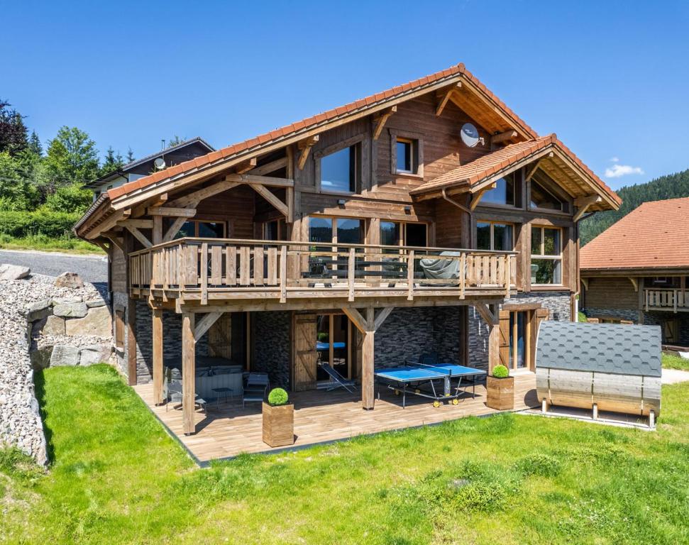 une maison en rondins avec une terrasse et un banc dans l'établissement Chalet Emeraude, chalet de luxe avec vue montagne, à Gérardmer