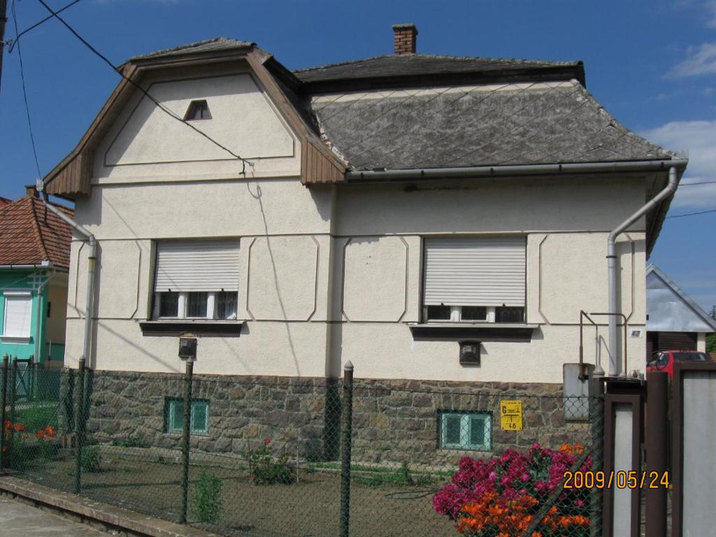 a white house with a gray roof at Muskátlis vendégház in Mátraderecske