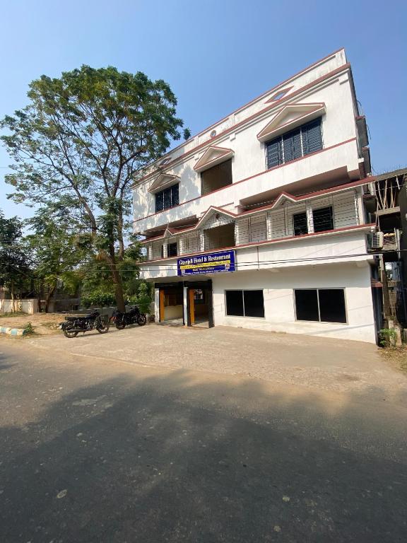桑蒂尼盖登Gitanjali Hotel & Restaurant的一座白色的大建筑,前面有自行车停放