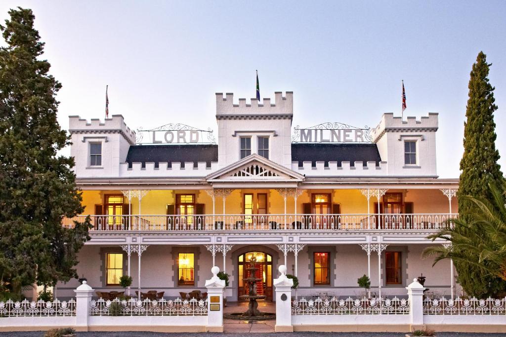 a large white mansion with a white fence at Lord Milner Hotel in Matjiesfontein