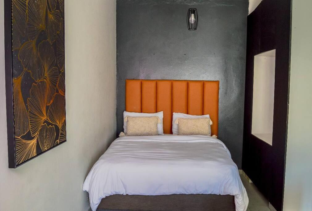 a bed with an orange headboard in a room at Cosy apt 5min to Sandton City 14 in Johannesburg