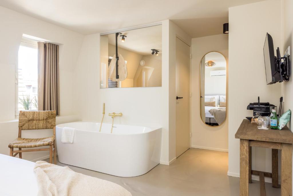 een witte badkamer met een bad in de kamer bij Boutiquehotel Omnia in Valkenburg