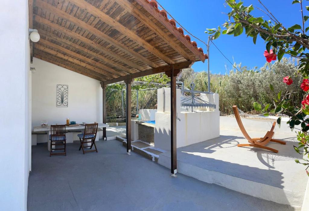 un patio con techo de madera, mesa y sillas en Lefakis cottage, en Órmos
