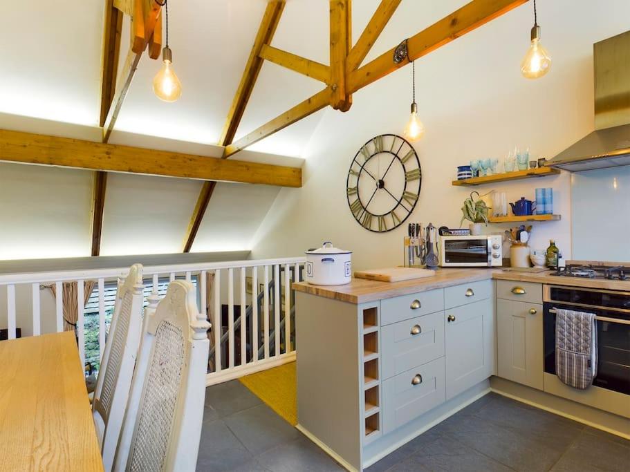 a kitchen with a table and a clock on the wall at Cornwall Truro Falmouth cottage in Perranwell