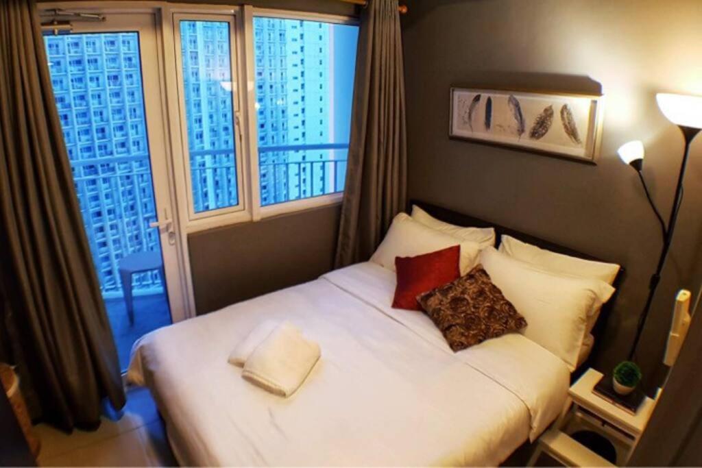 a bedroom with a white bed with two pillows at HOMEY MAKATI CONDO UNIT with NETFLIX in Manila