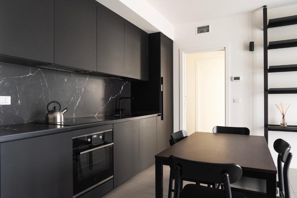 a kitchen with black cabinets and a table with chairs at San Siro Fiera - Youhosty in Milan