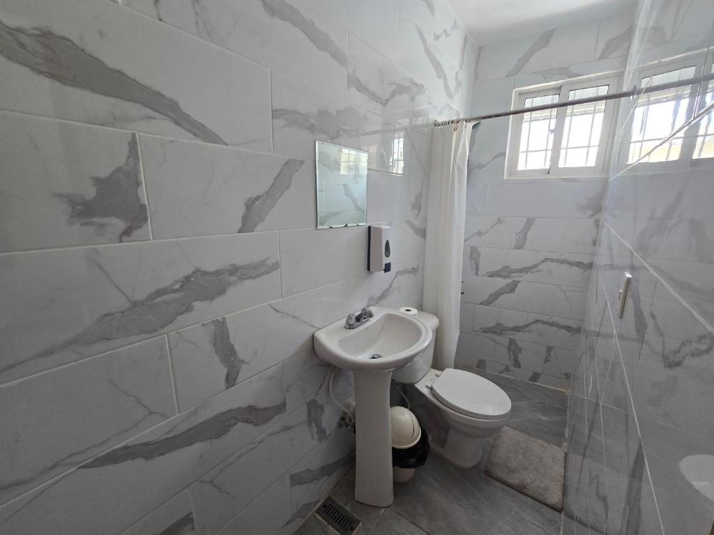 a white bathroom with a toilet and a sink at Hostal 53 Boutique Santo Domingo in Santo Domingo