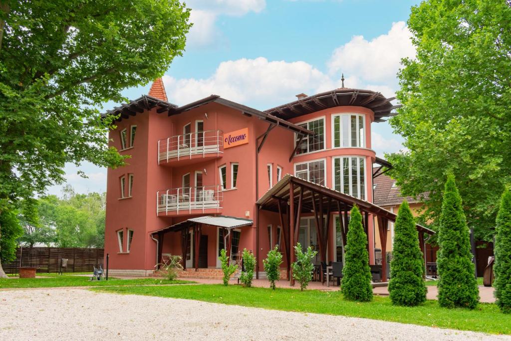 a large pink building with trees in front of it at Accomo Apartmanház in Siófok