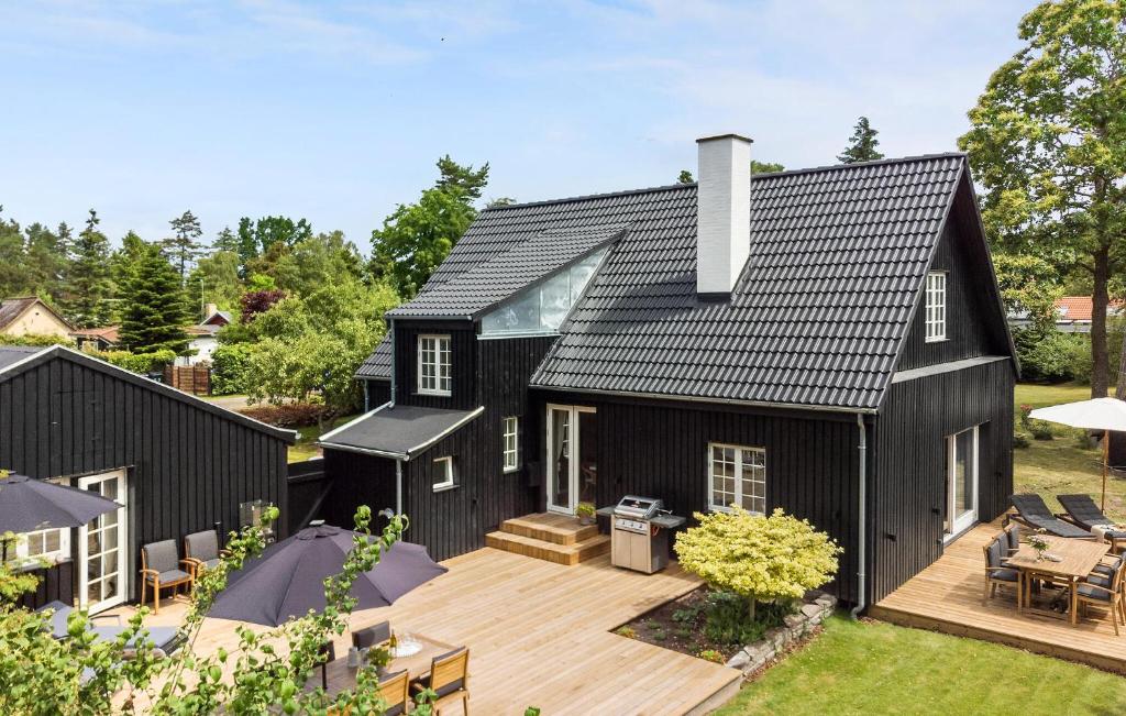 an exterior view of a black house with a wooden deck at 5 Bedroom Nice Home In Væggerløse in Marielyst