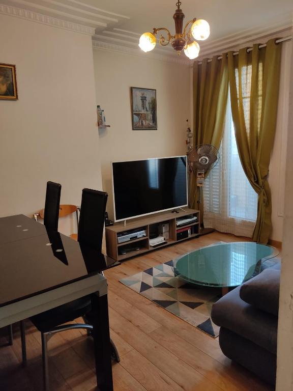 un salon avec une télévision à écran plat et une table dans l'établissement Appartement spacieux avec une belle vue sur le Tribunal de Paris, à Paris