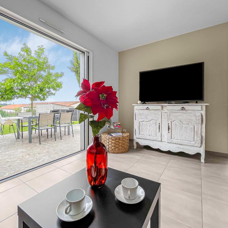 un salon avec un vase avec une fleur rouge sur une table dans l'établissement gîte de Marko et Mag à Oudon, à Oudon