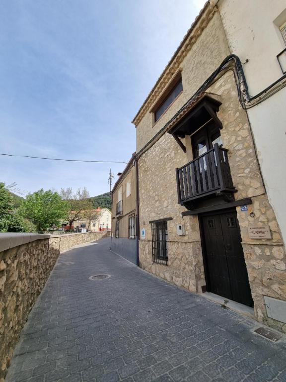 a stone building with a black door and a balcony at Alojamiento Rural El Pontón in Pontones