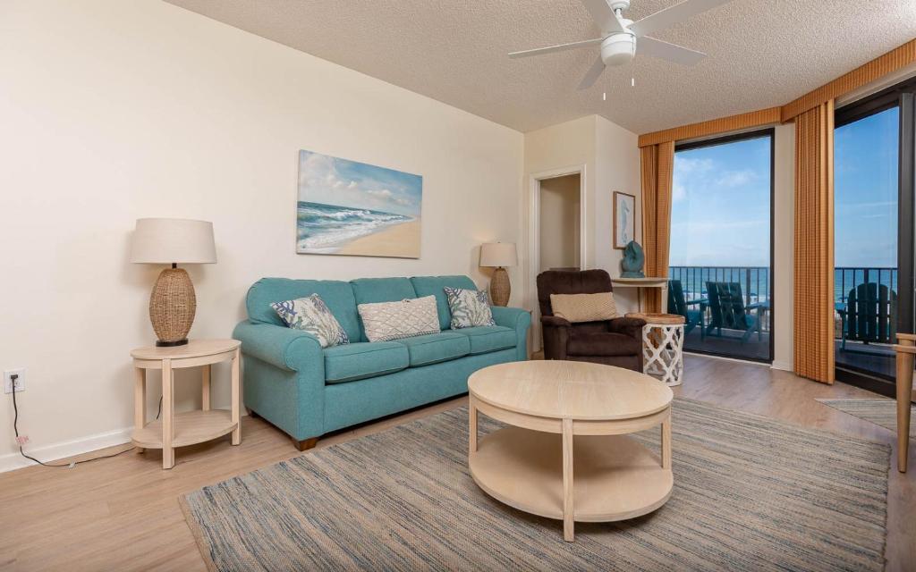 a living room with a blue couch and a table at Phoenix X 212 condo in Orange Beach