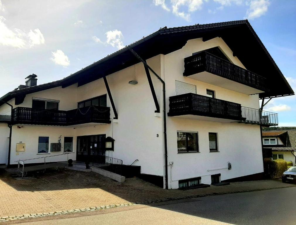 Un edificio blanco con balcones a los lados. en Haus Naturenergie, en Frauenau