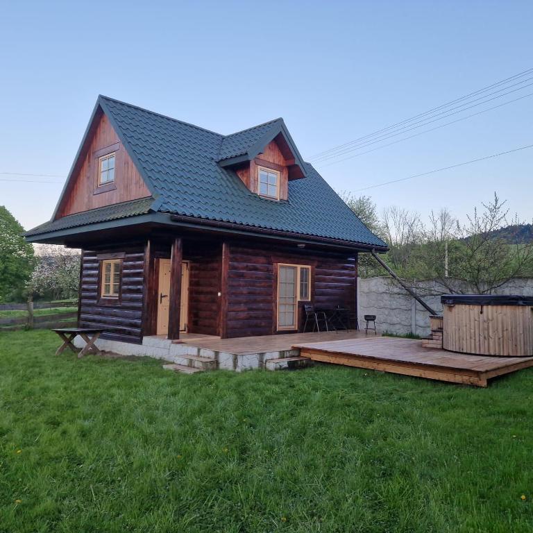 a log cabin with a deck in a yard at Serce Beskidu Niskiego in Świątkowa Mała