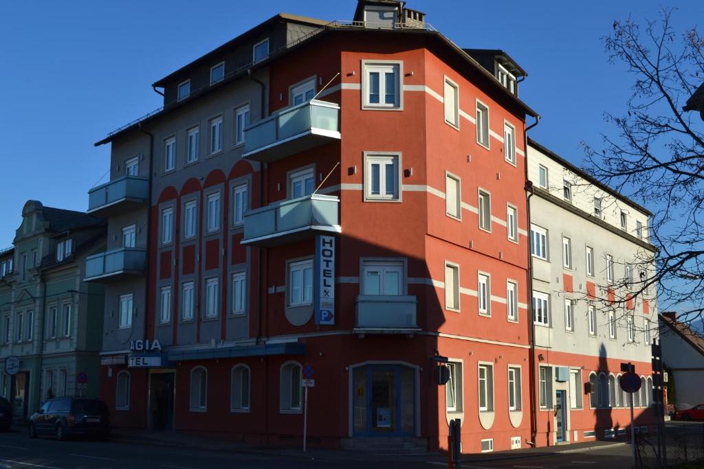 a tall red building with white windows on a street at Hotel Aragia in Klagenfurt