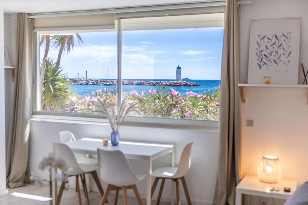 une salle à manger avec une fenêtre donnant sur l'océan dans l'établissement Beau 2P bord de mer, Marina baie des anges, à Villeneuve-Loubet