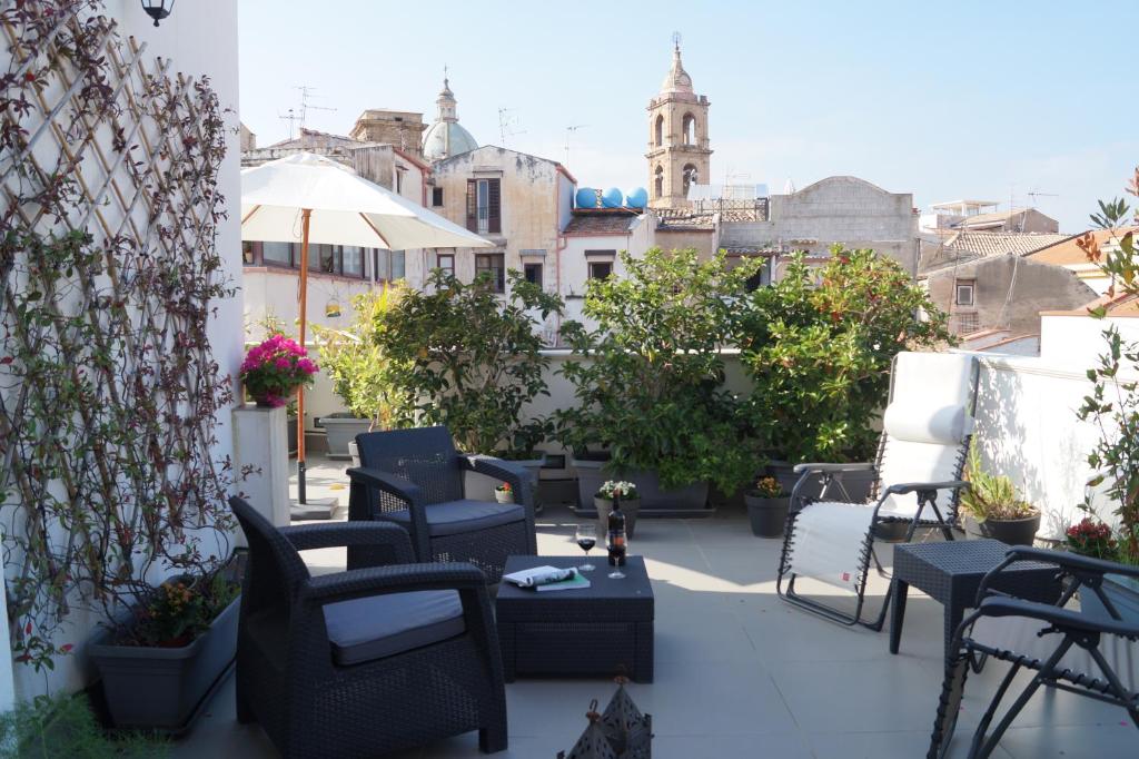 un patio con sillas y mesas en un balcón en Guascone Apartments, en Palermo