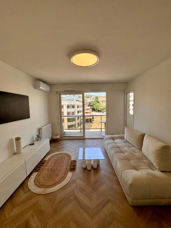 - un salon avec un grand canapé et une télévision dans l'établissement Charmant 2P Moderne et Épuré Près de la Mer et de la Célèbre Promenades des Anglais - Vivez le Rêve Méditerranéen, à Nice