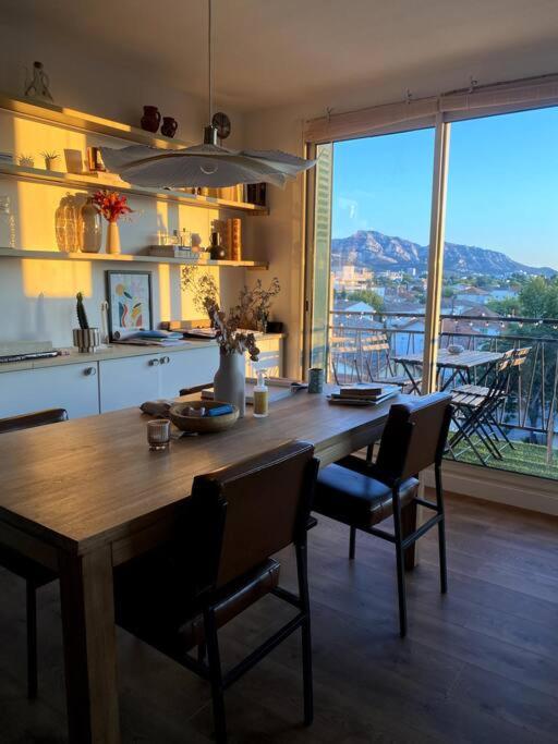 une cuisine avec une table et des chaises ainsi qu'une grande fenêtre dans l'établissement Magnifique vue - 500m Vélodrome, Plages, Borely, à Marseille