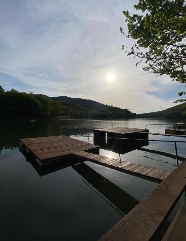 a dock on a lake with the sun setting on the water at Gretas Home Surduc in Fîrdea