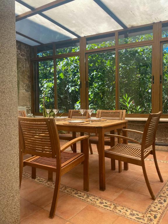 a wooden table and chairs in a room with windows at Casa Príncipe 12 in Cambados