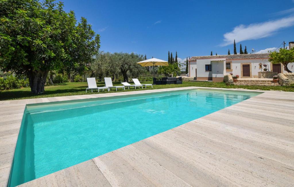 a swimming pool with two chairs and a house at Tenuta Flaccavento in Chiaramonte Gulfi