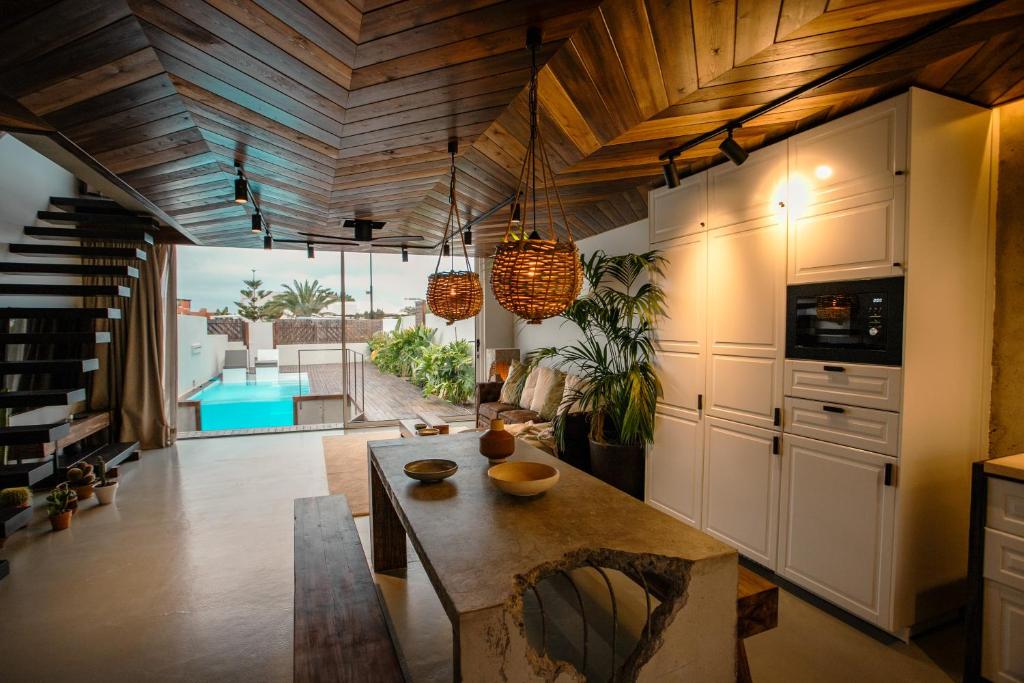 a kitchen with wooden ceilings and a dining room at Casa OuirA Chalet con Piscina Privada y vistas in Corralejo