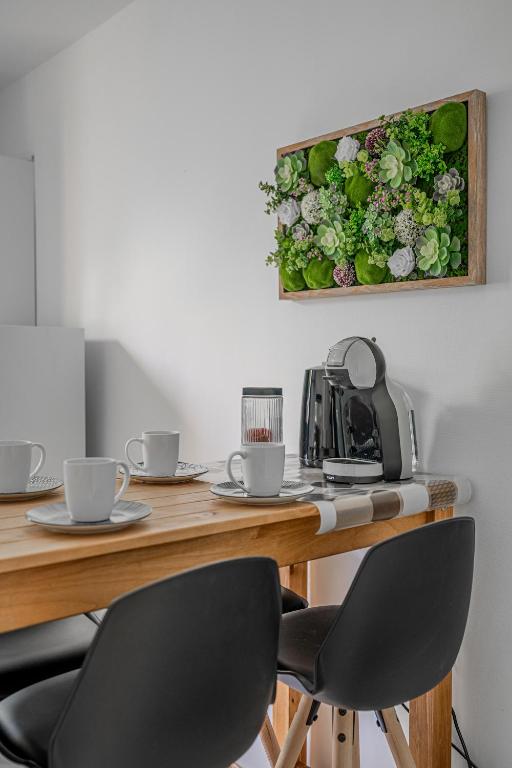 une table avec deux chaises et un tableau de fleurs sur le mur dans l'établissement Le Jardin Secret, à Seyssinet-Pariset