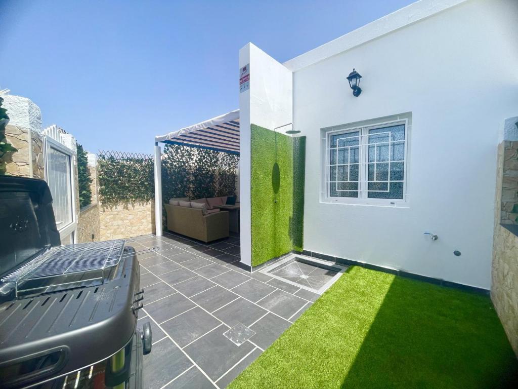 a patio with green grass and a white house at Bright Place Bungalow in San Bartolomé