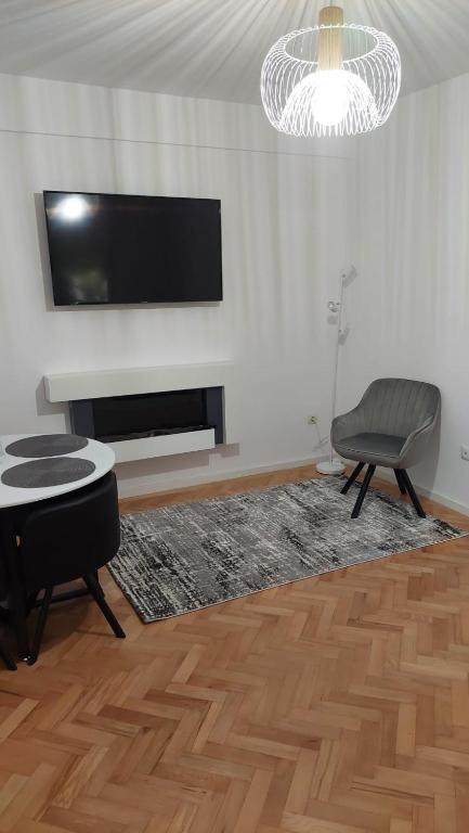 a living room with a flat screen tv and a chair at Helen Apartament in Craiova