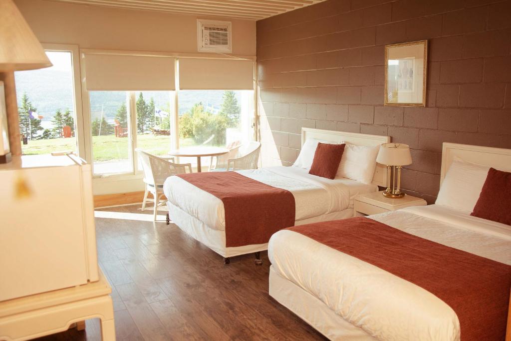 a bedroom with two beds and a table and a window at Travels Inn Victoria County in Boularderie East