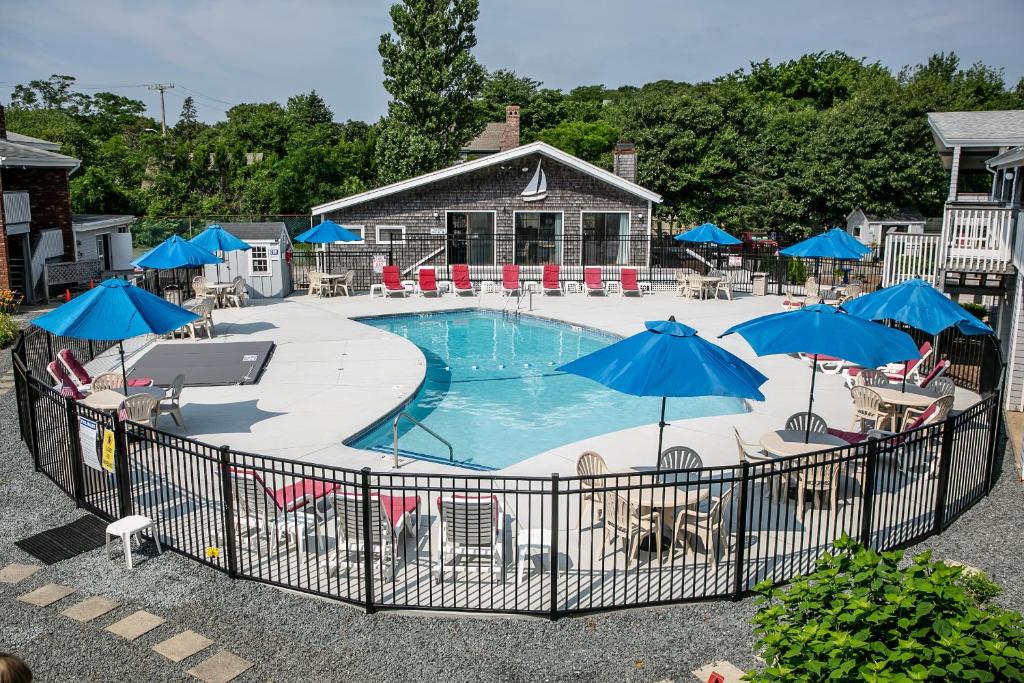 a pool with blue umbrellas and chairs and tables at Eastwood at Provincetown in Provincetown